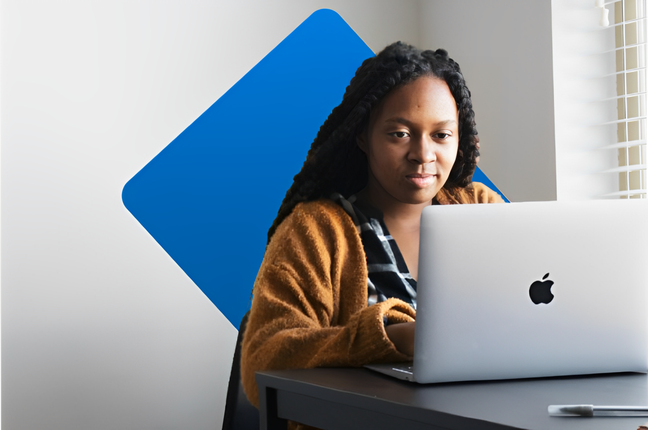 Mulher na frente de um computador da marca macbook